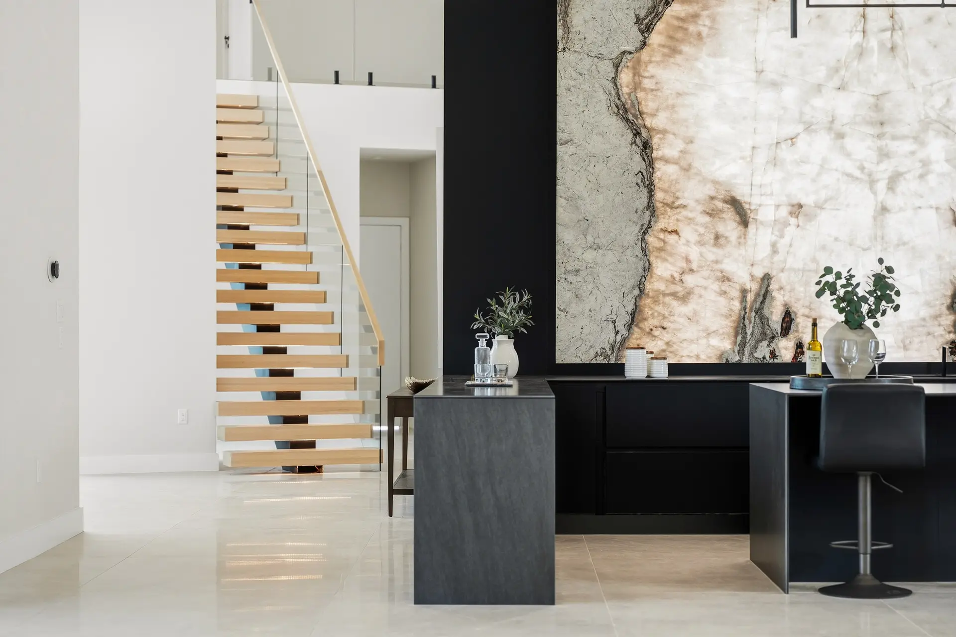 Bluewater Residence floating staircase and bar beside backlit stone wall in Lago Vista, Texas