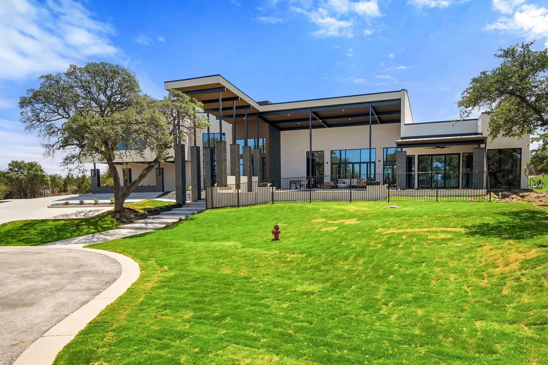 Bluewater Residence side exterior with stone columns and steel-framed canopy in Lago Vista, Texas