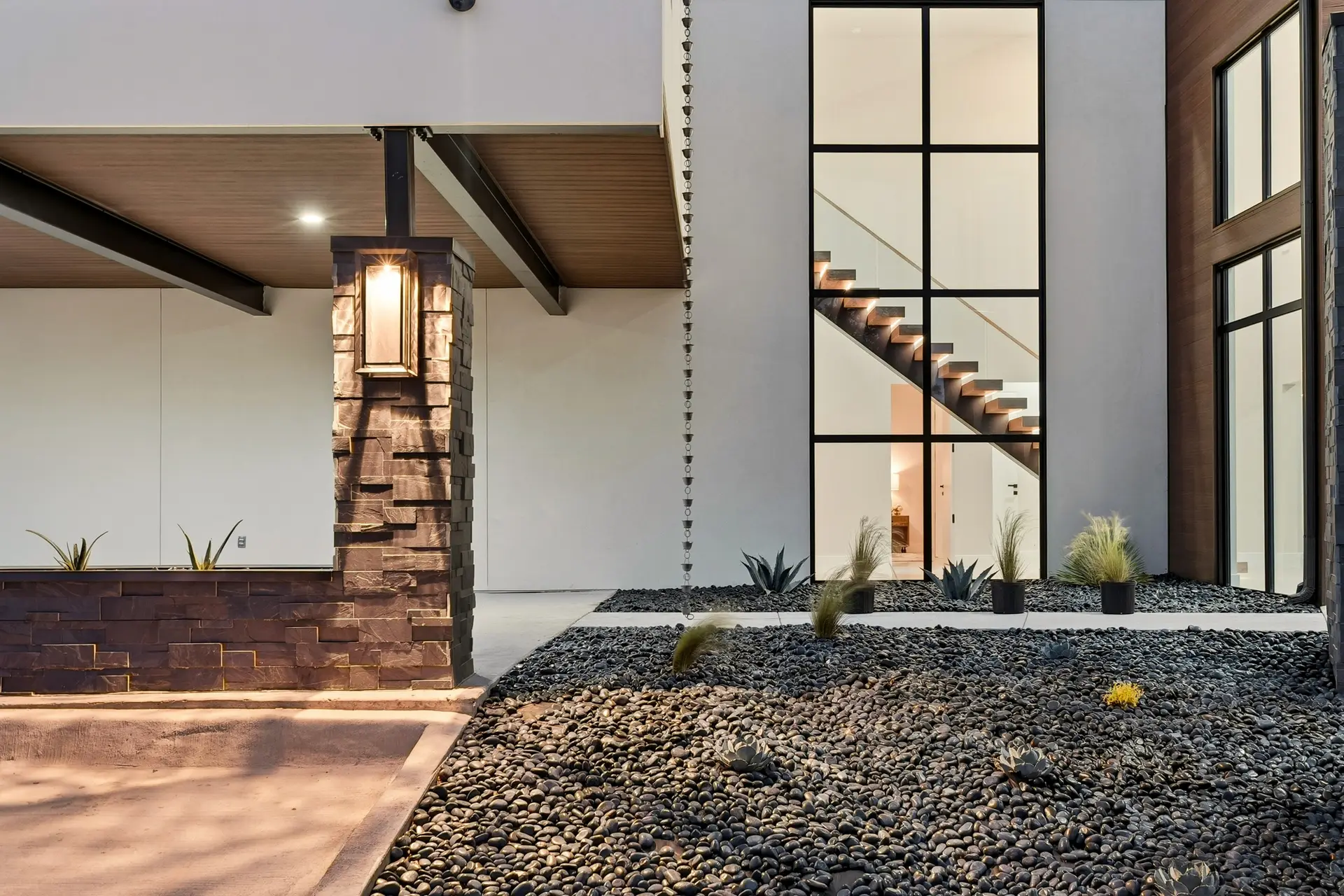 Bluewater Residence stone lantern column, pebble landscaping and tall stair window in Lago Vista, Texas