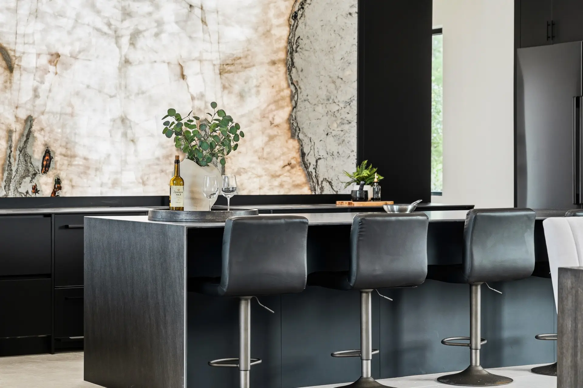 Bluewater Residence kitchen island with bar stools and backlit stone backsplash in Lago Vista, Texas