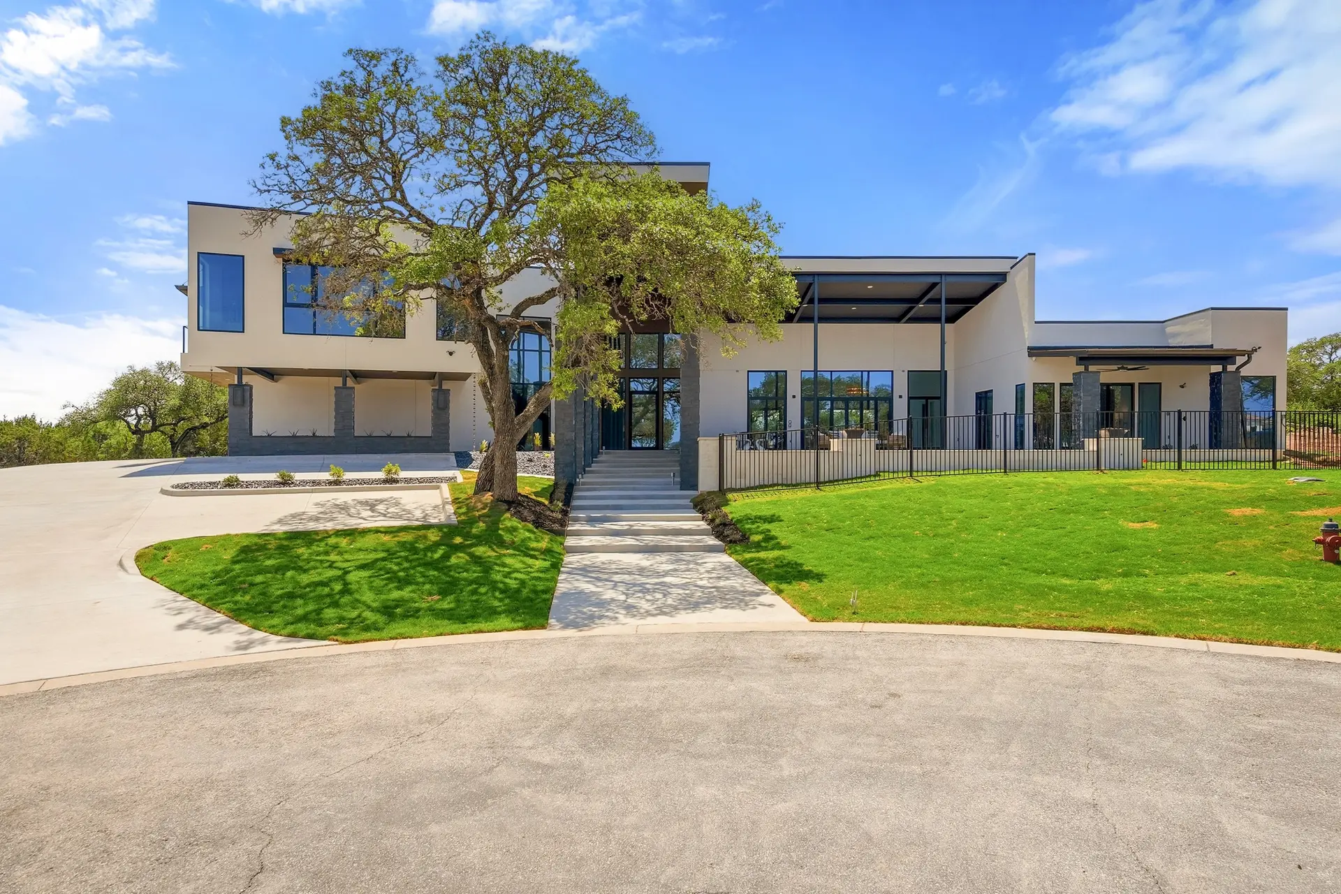 Bluewater Residence daytime front facade with oak tree, lawn and driveway in Lago Vista, Texas