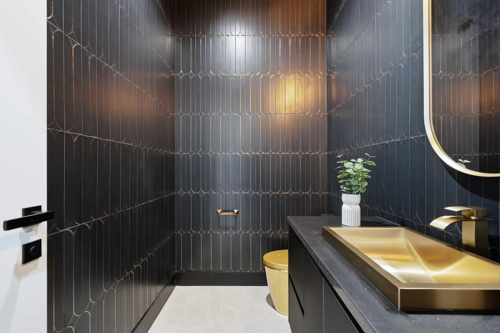Bluewater Residence powder room with black patterned tile and gold sink in Lago Vista, Texas